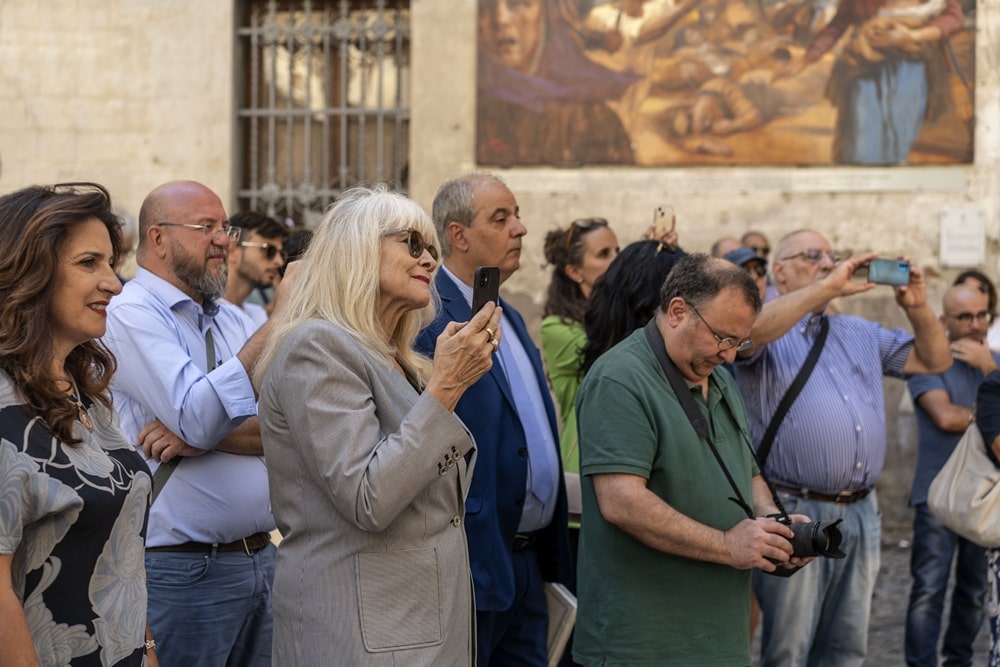 Scorcio del pubblico radunato nella piazzetta S. Giovanni Gerosolimitano (la signora bionda in primo piano è Mary Reid, moglie di Gino Gaudio) - Image credit:  Open Fields Productions